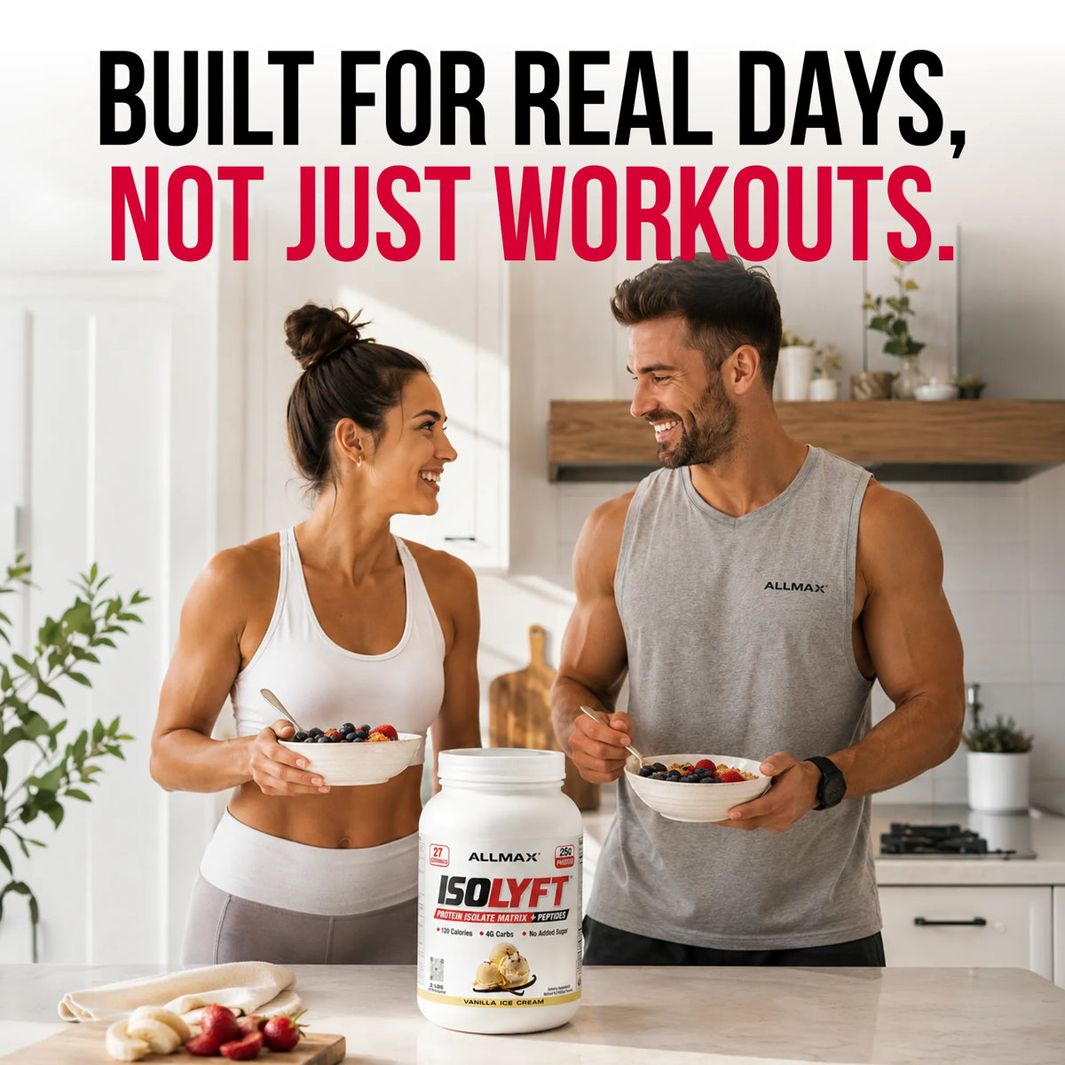 A man and a woman in athletic wear stand in a bright kitchen holding bowls of fruit and protein powder. A large tub of ALLMAT ISOLYFT protein powder sits on the counter in front of them, with bold text at the top reading 'BUILT FOR REAL DAYS, NOT JUST WORKOUTS.